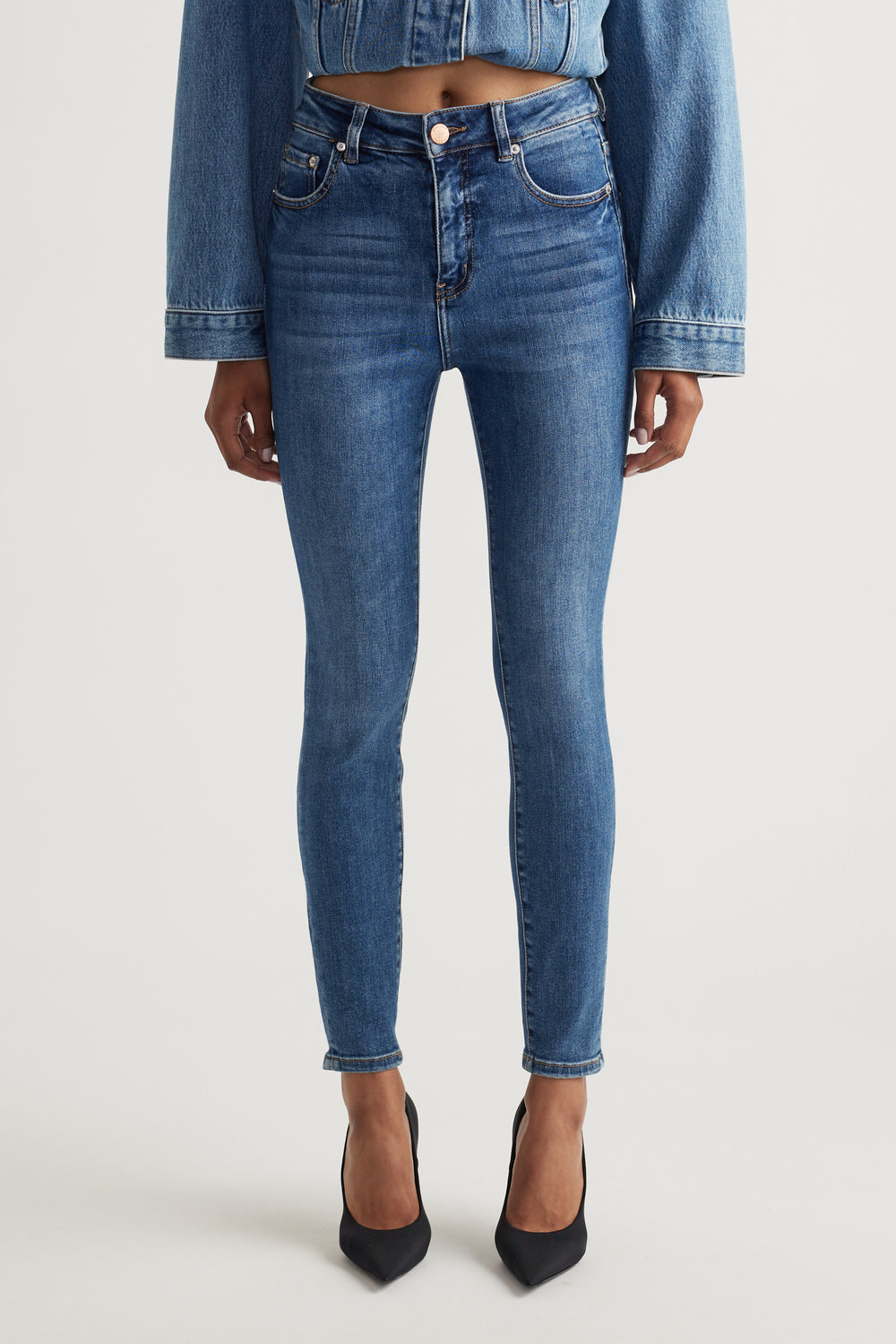 Front view of Evie High Rise Skinny Jean in medium blue denim, gallery position 2, portrait orientation, styled with heels and cropped jacket.