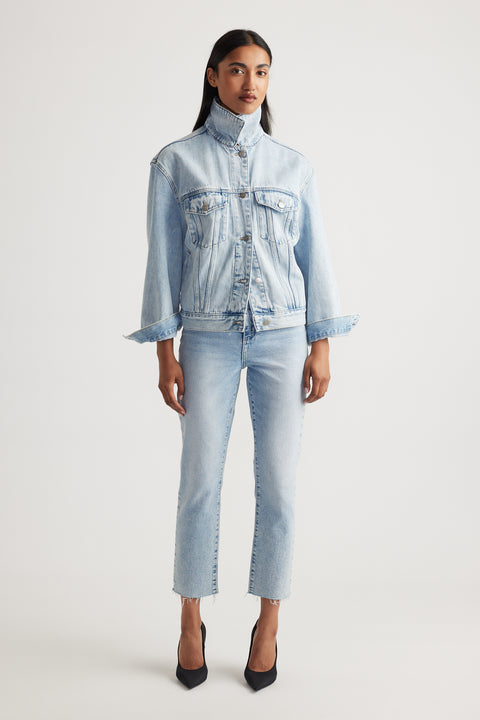 Woman wearing a light blue denim jacket and cropped straight jeans on a white background