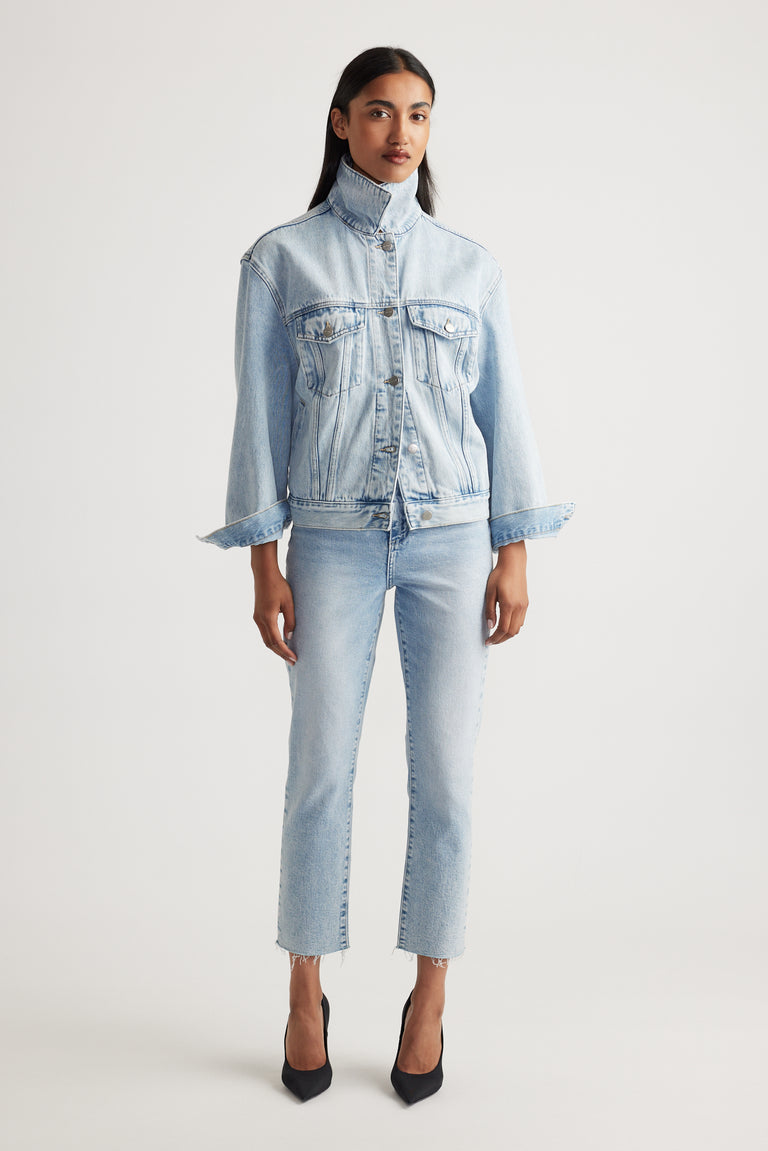 Woman wearing a light blue denim jacket and cropped straight jeans on a white background