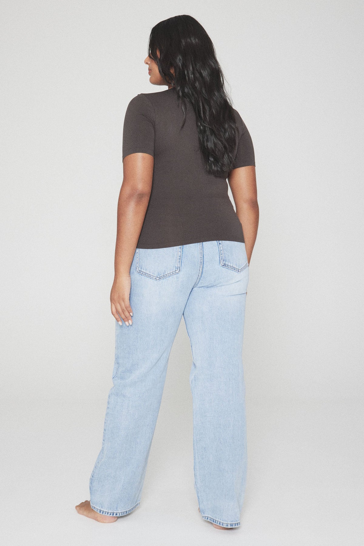 Woman wearing a fitted brown short sleeve tee with light blue jeans
