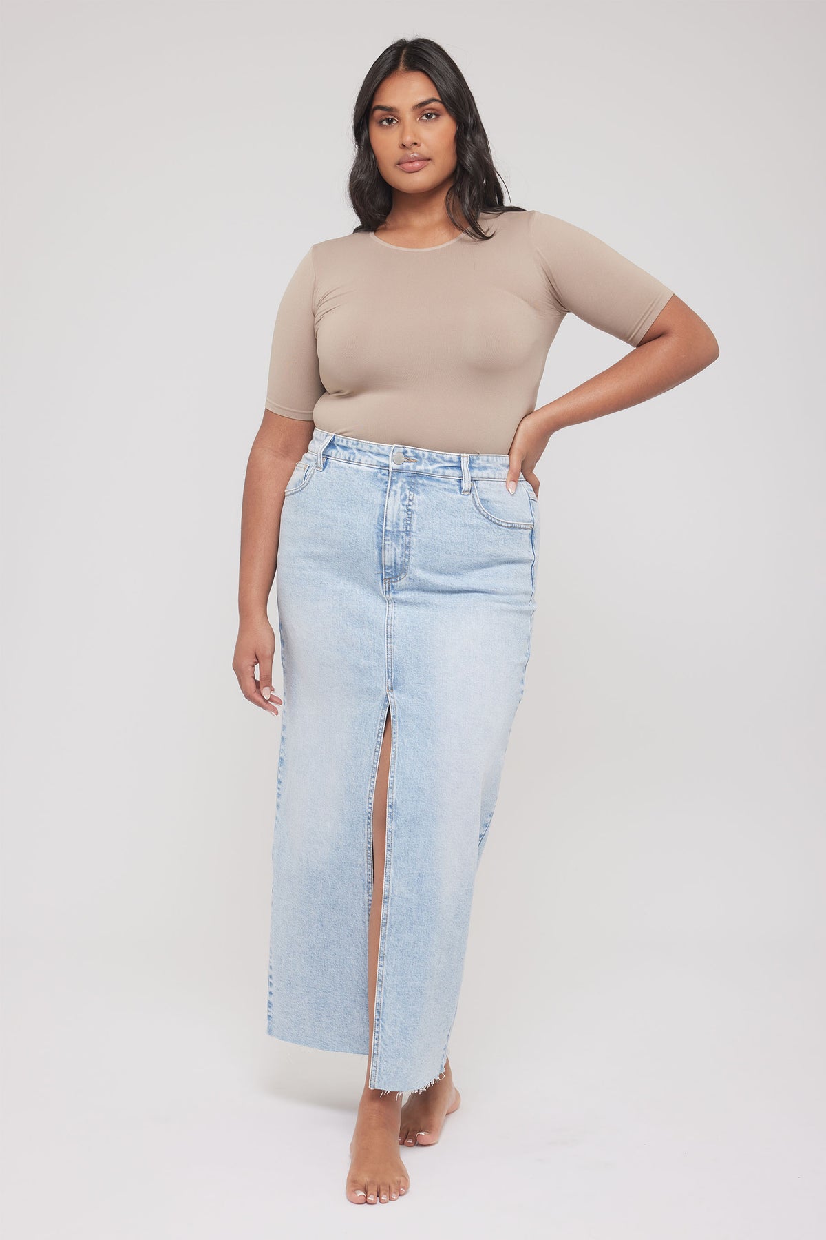 Woman wearing a beige fitted short sleeve tee with light wash jeans