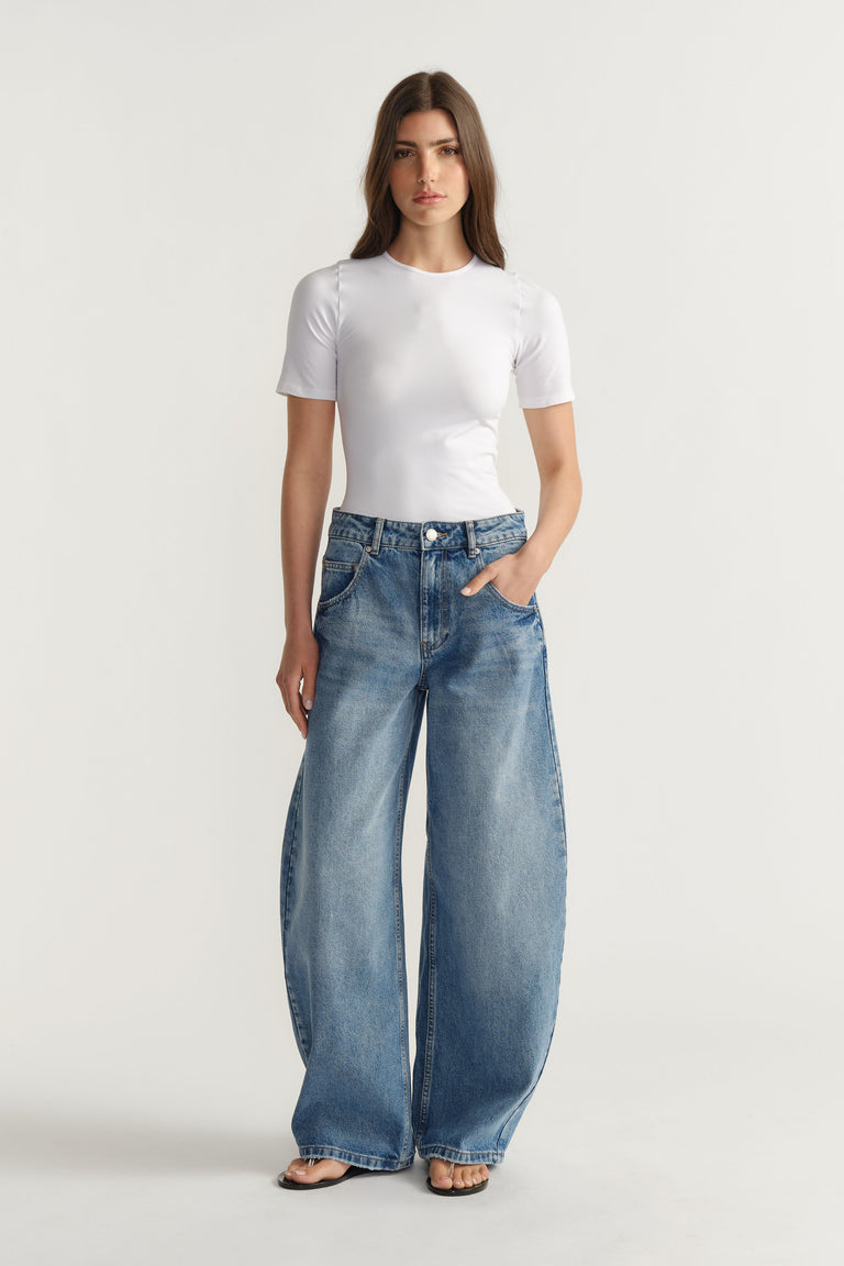 Woman wearing a fitted white tee paired with relaxed wide-leg blue denim jeans and open-toe sandals for an effortless look