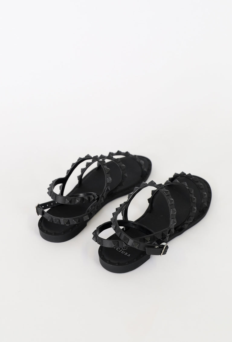 Black strappy flat sandals featuring studded detailing and an adjustable buckle for a chic, everyday look.