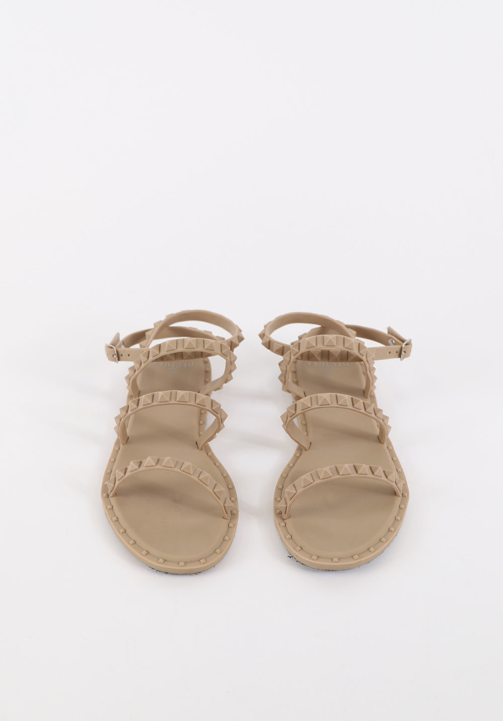 Beige flat sandals featuring studded straps with adjustable buckles for a stylish and comfortable fit.