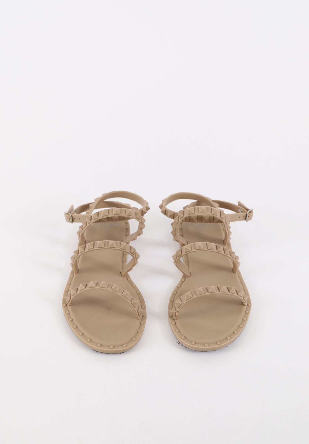 Beige flat sandals featuring studded straps with adjustable buckles for a stylish and comfortable fit.