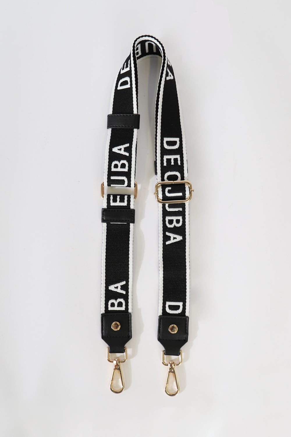 Black and white adjustable strap with gold hardware and bold lettering spelling DECJUBA on fabric bands.