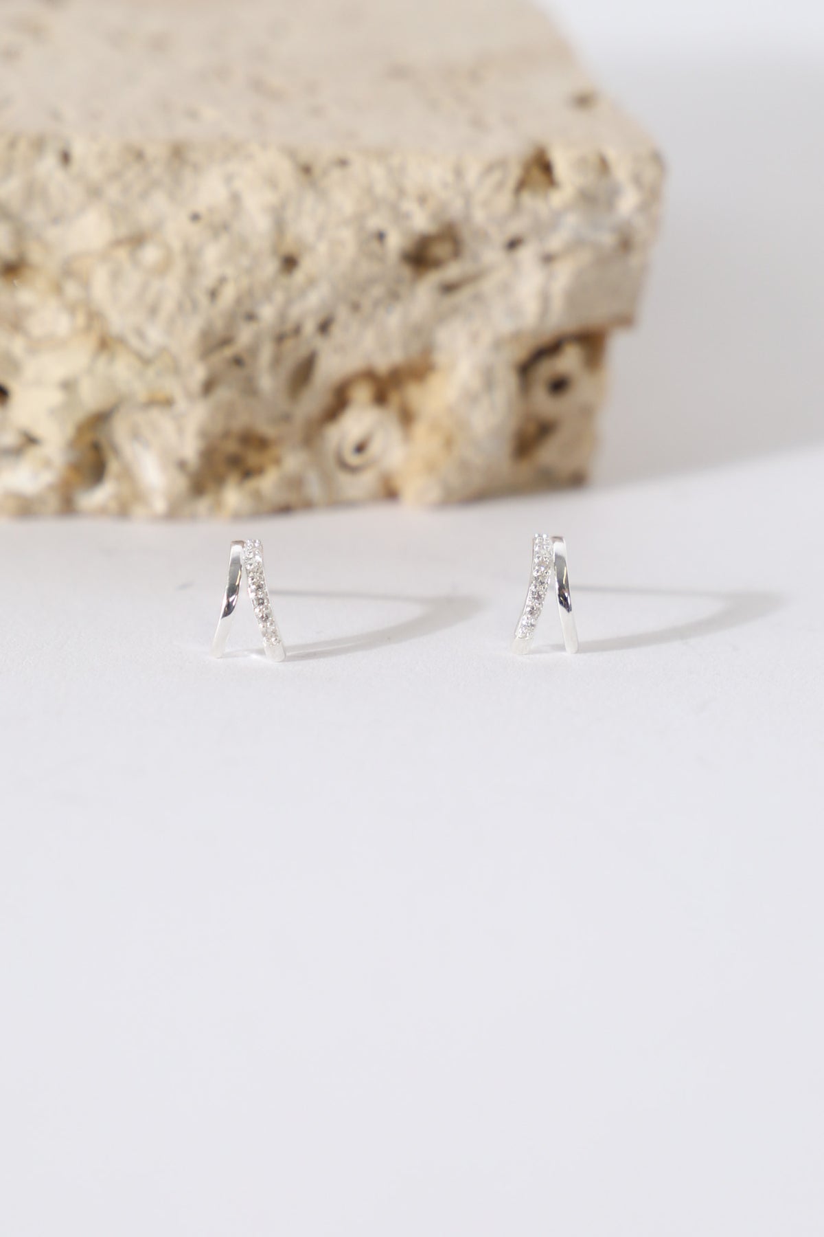 Pair of delicate double stone set earrings displayed on a white surface
