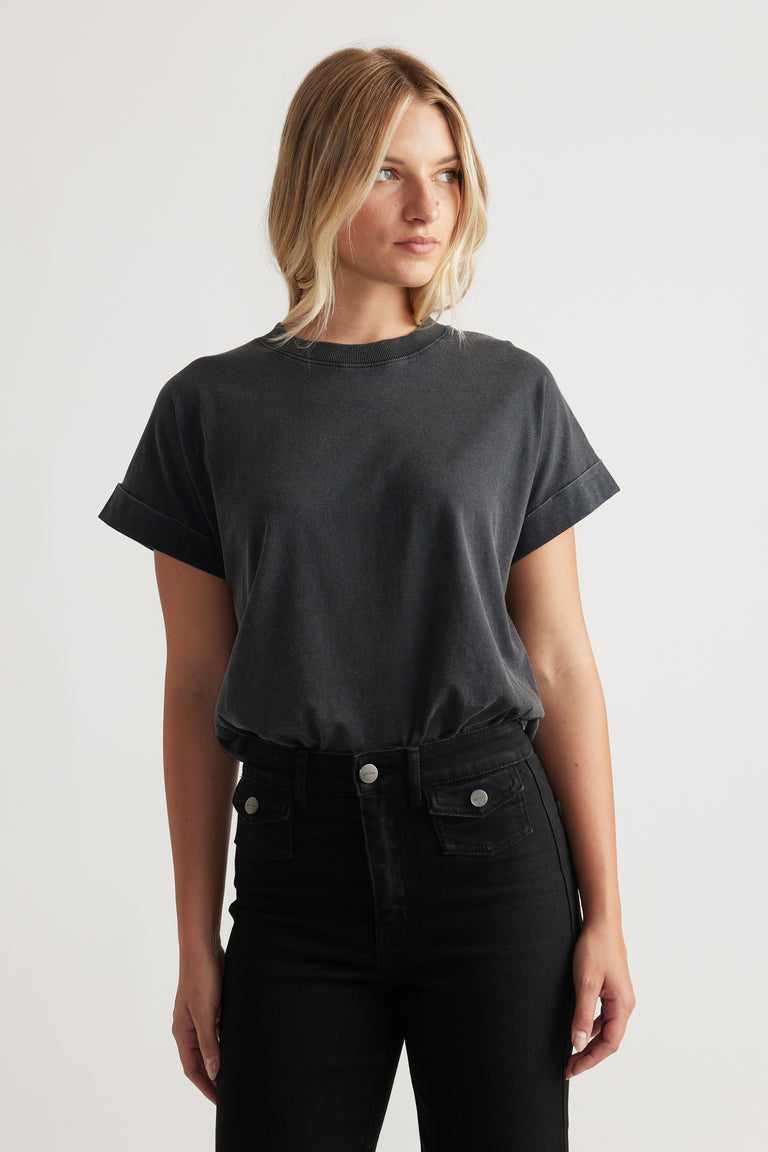 Woman wearing a relaxed dark grey crew neck tee with rolled sleeves paired with high-waisted black jeans for a casual look