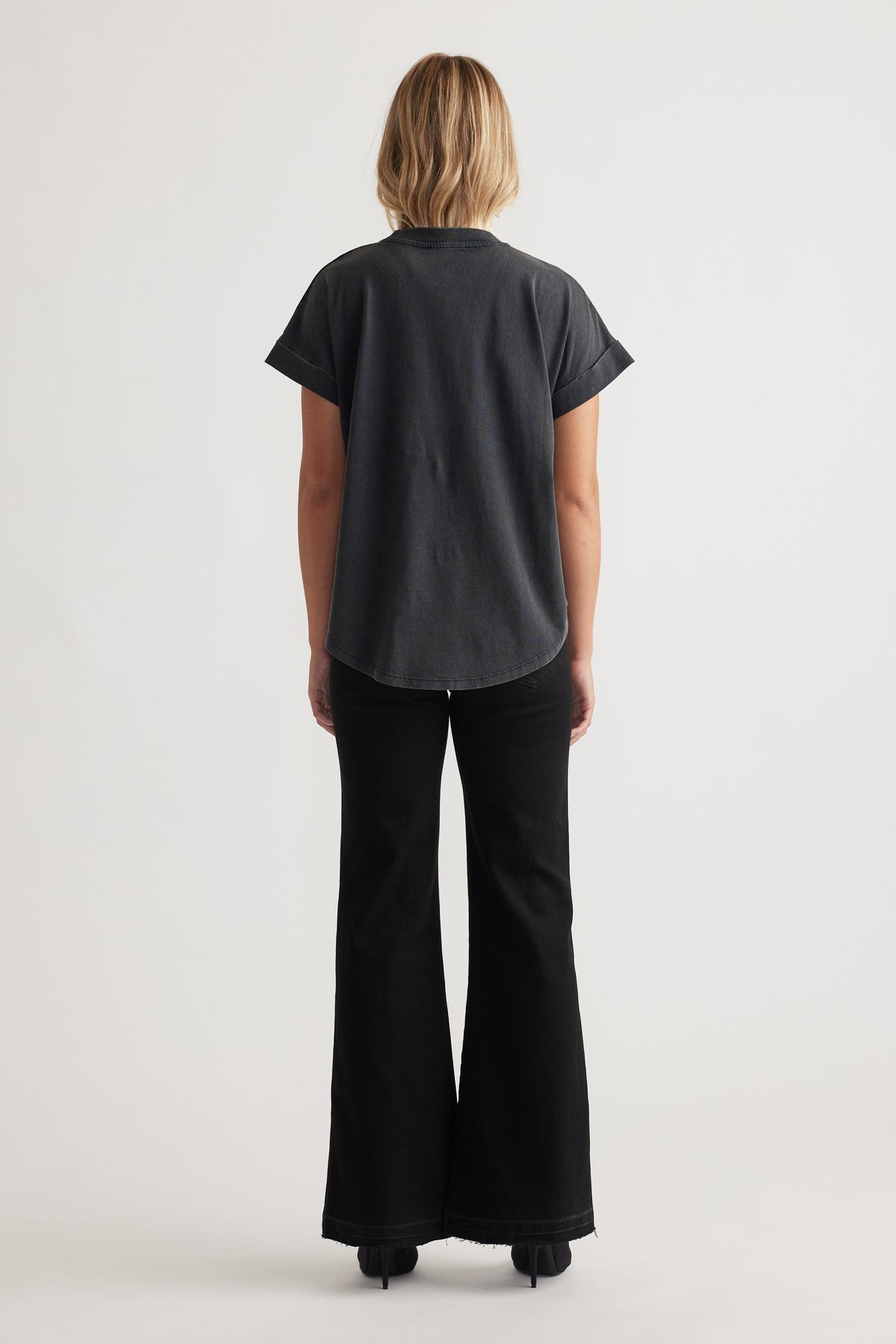 Woman seen from behind wearing a relaxed black Chloe Crew Tee with cuffed short sleeves and black flared pants for a chic vibe