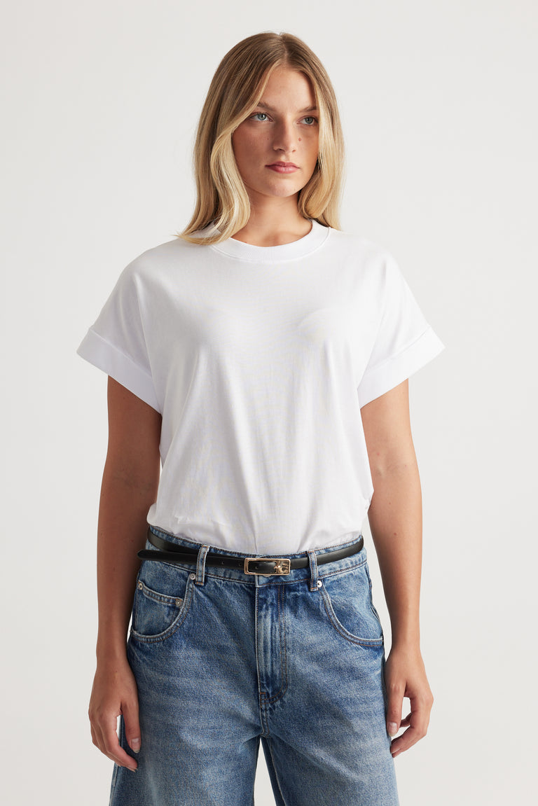 Woman wearing a white crew neck tee with rolled cuffs and relaxed blue jeans