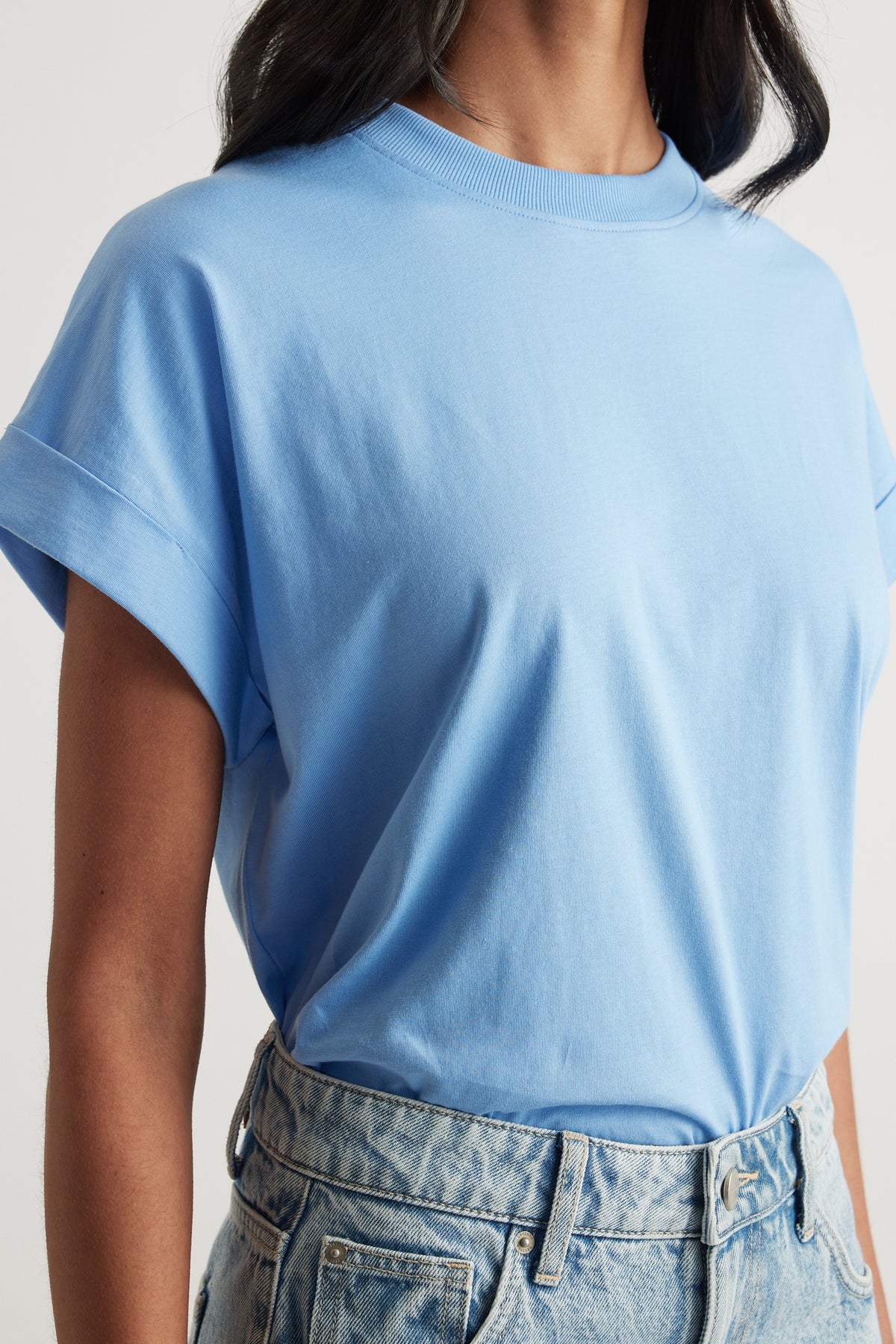 Woman wearing a light blue crew neck tee with high-waisted light wash jeans