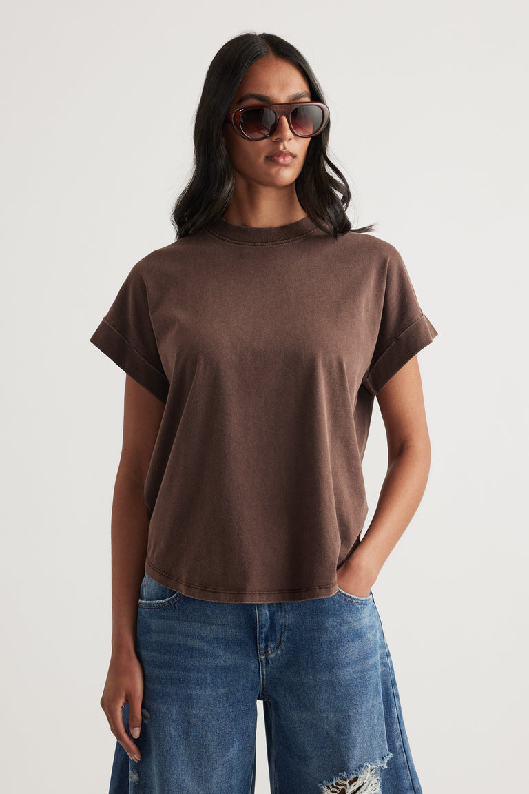 Woman wearing a brown crew neck tee with blue distressed jeans and oversized sunglasses