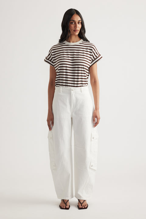 Woman wearing a brown and white striped short sleeve tee with rolled cuffs and high-waisted white wide-leg pants with pockets