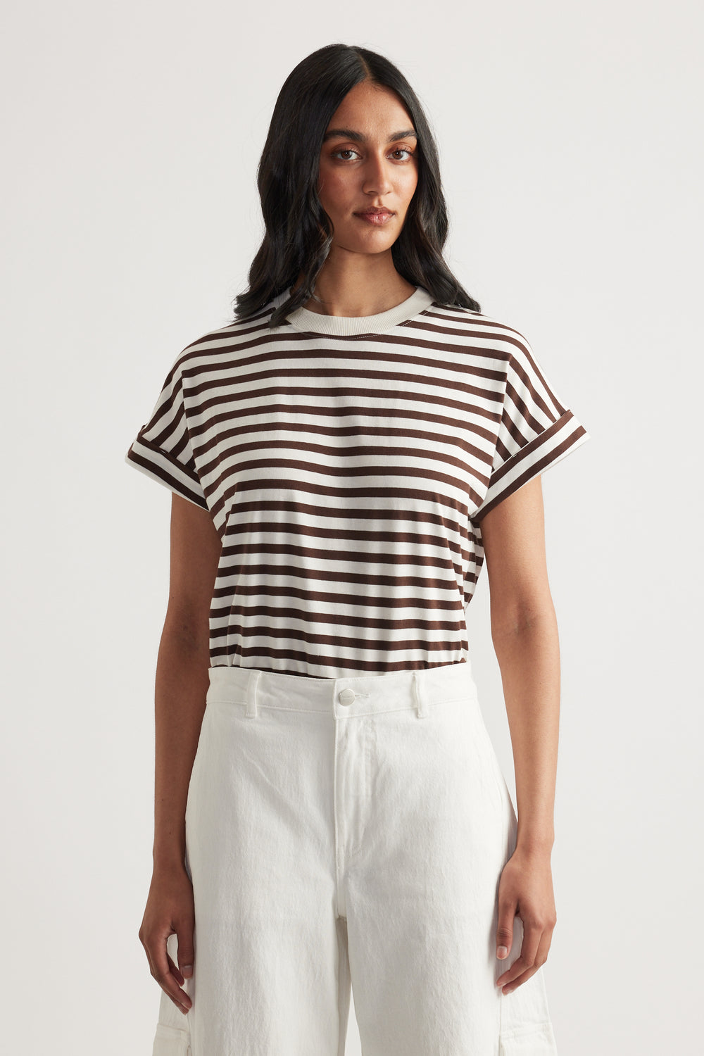 Woman wearing a brown and white striped short sleeve tee with rolled cuffs paired with high-waisted white pants
