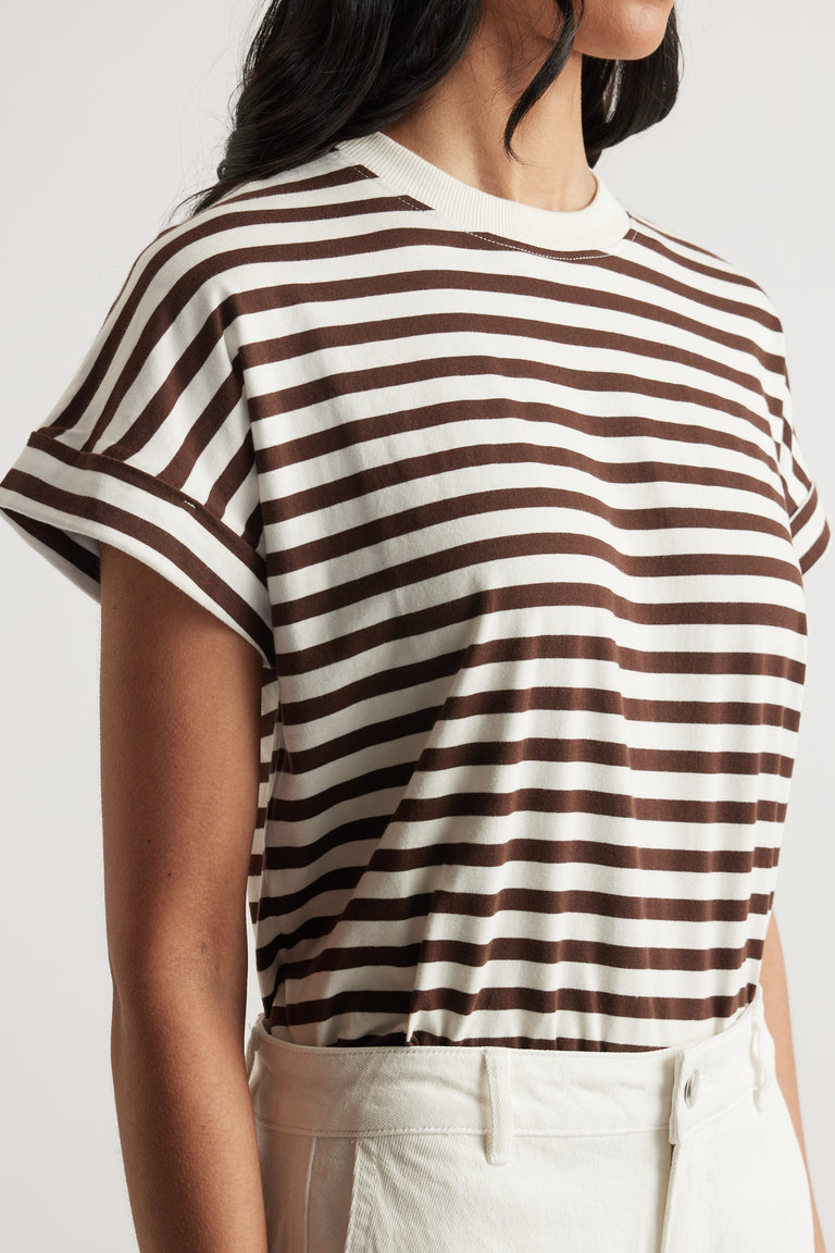 Close-up of woman wearing a brown and white striped short sleeve tee with rolled cuffs tucked into high-waisted white pants