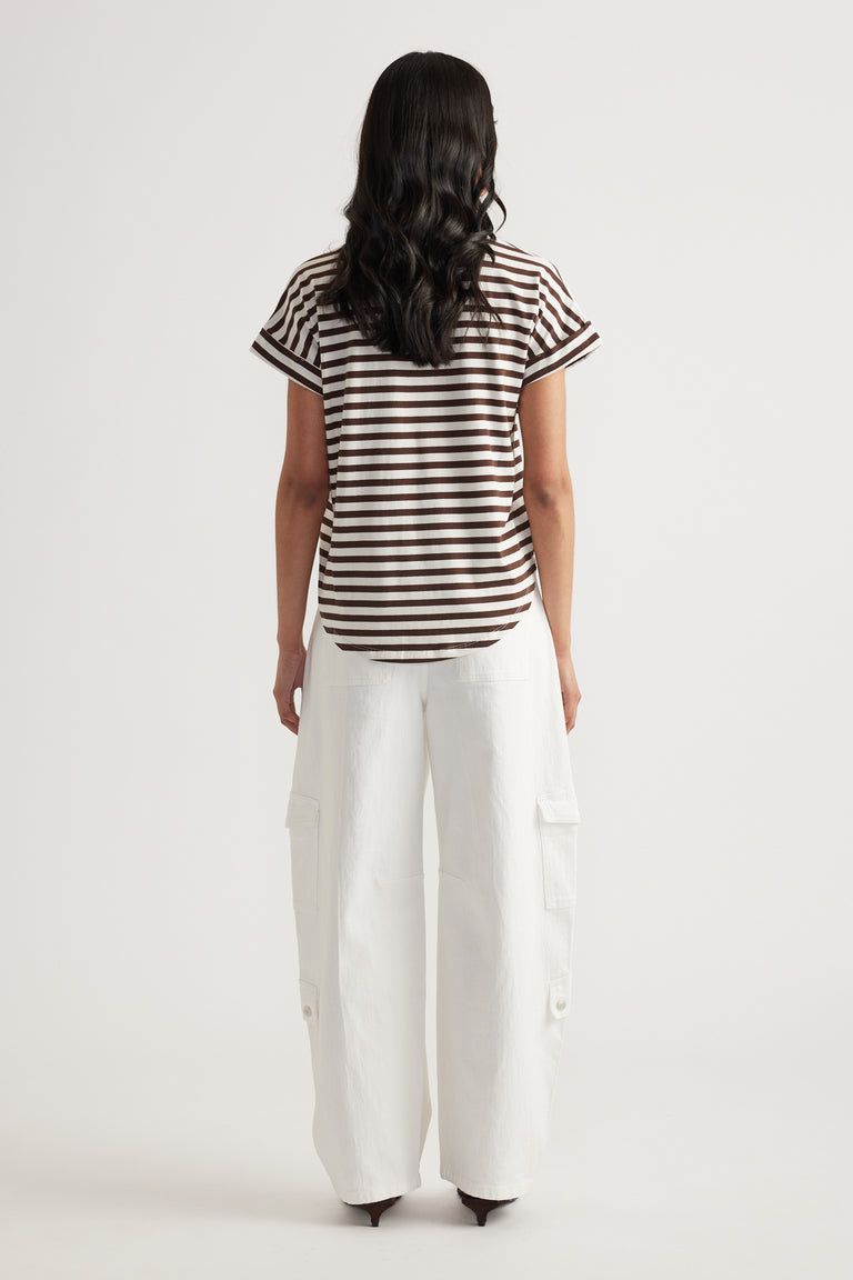 Rear view of woman wearing brown and white striped short sleeve tee paired with loose white cargo pants
