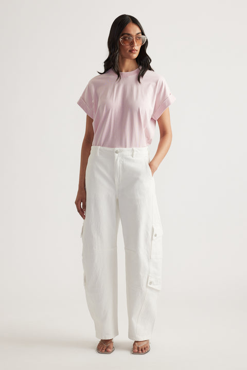 Woman wearing a pale pink crew neck tee with rolled cuffs, white cargo pants and sunglasses