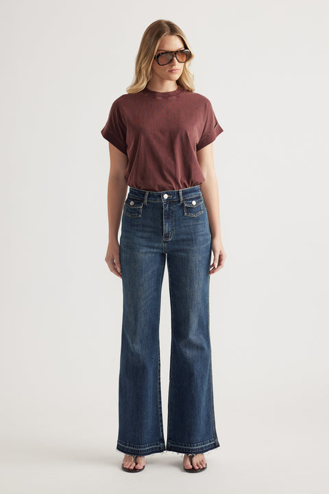 Woman in a burgundy crew neck tee with rolled cuffs and dark blue wide-leg jeans, styled with sunglasses and sandals