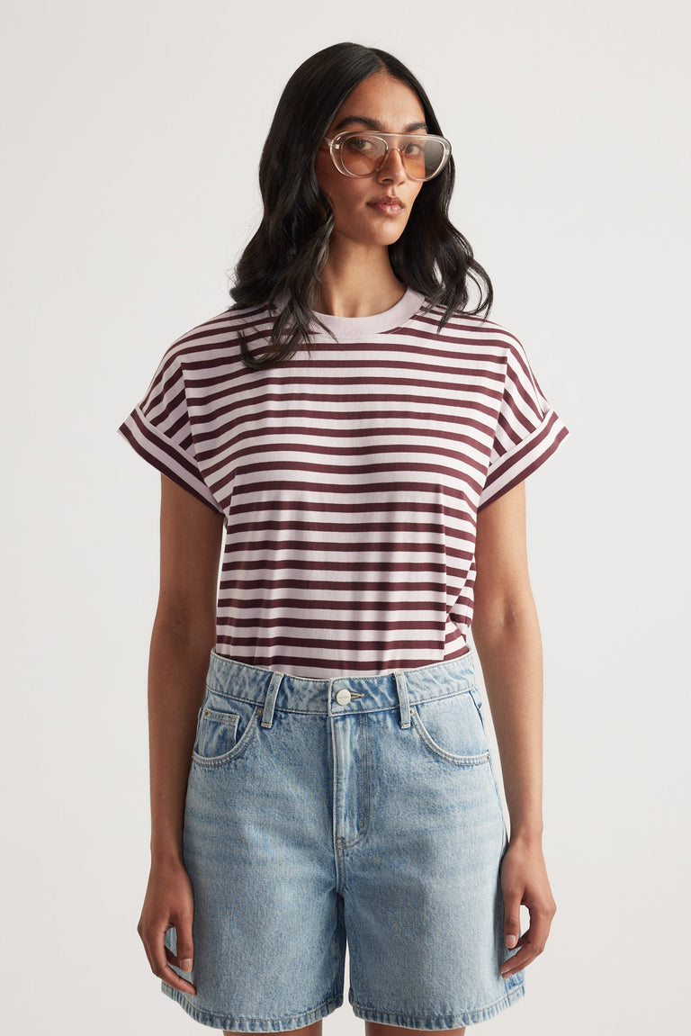Woman wearing a maroon and white striped rolled cuff tee paired with light wash high-rise denim shorts and oversized glasses
