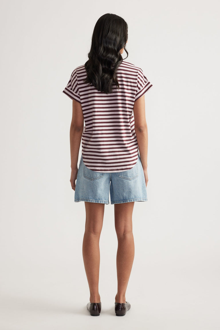 Rear view of woman wearing relaxed fit light blue denim shorts paired with a maroon and white striped rolled-cuff tee