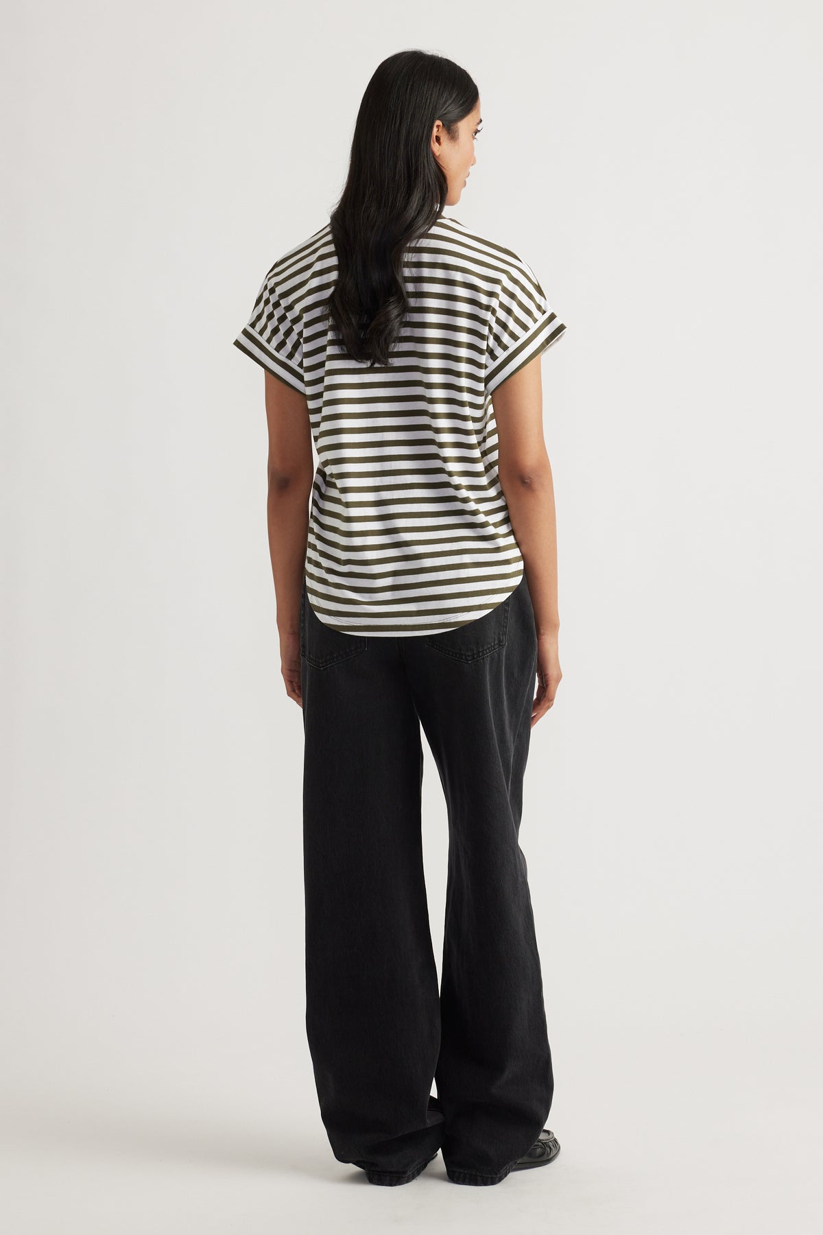 Woman in olive and white striped Chloe Crew Tee with cuffed sleeves paired with relaxed fit black wide-leg jeans seen from back
