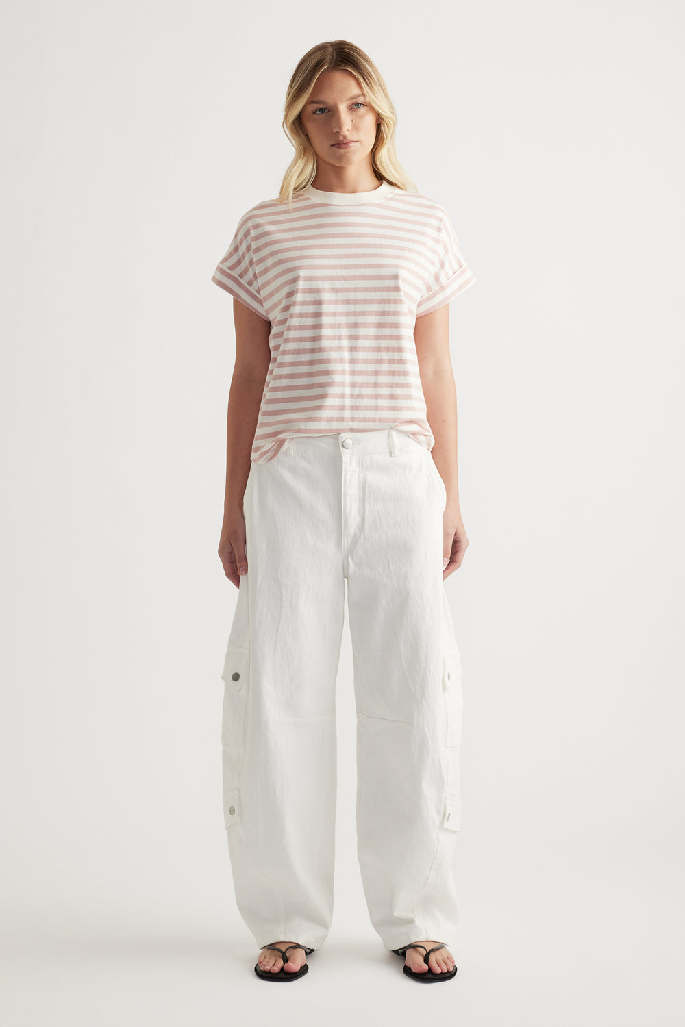 Woman wearing a pink and white striped crew neck tee with white wide leg pants and sandals