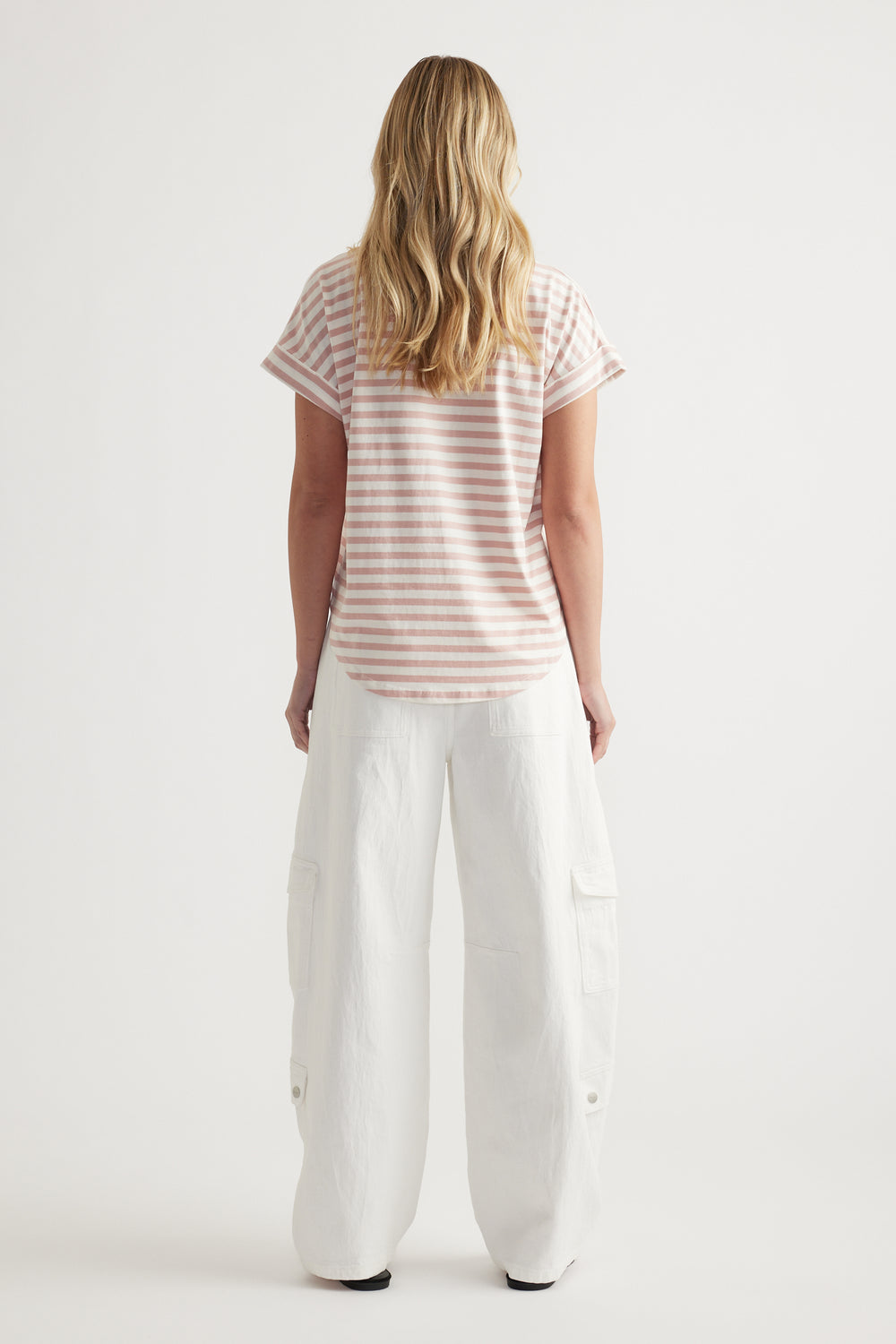 Woman viewed from behind wearing a pink and white striped crew neck tee with white wide leg pants