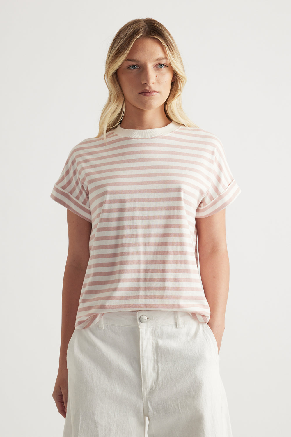 Woman wearing a pink and white striped crew neck tee with rolled cuffs and white pants