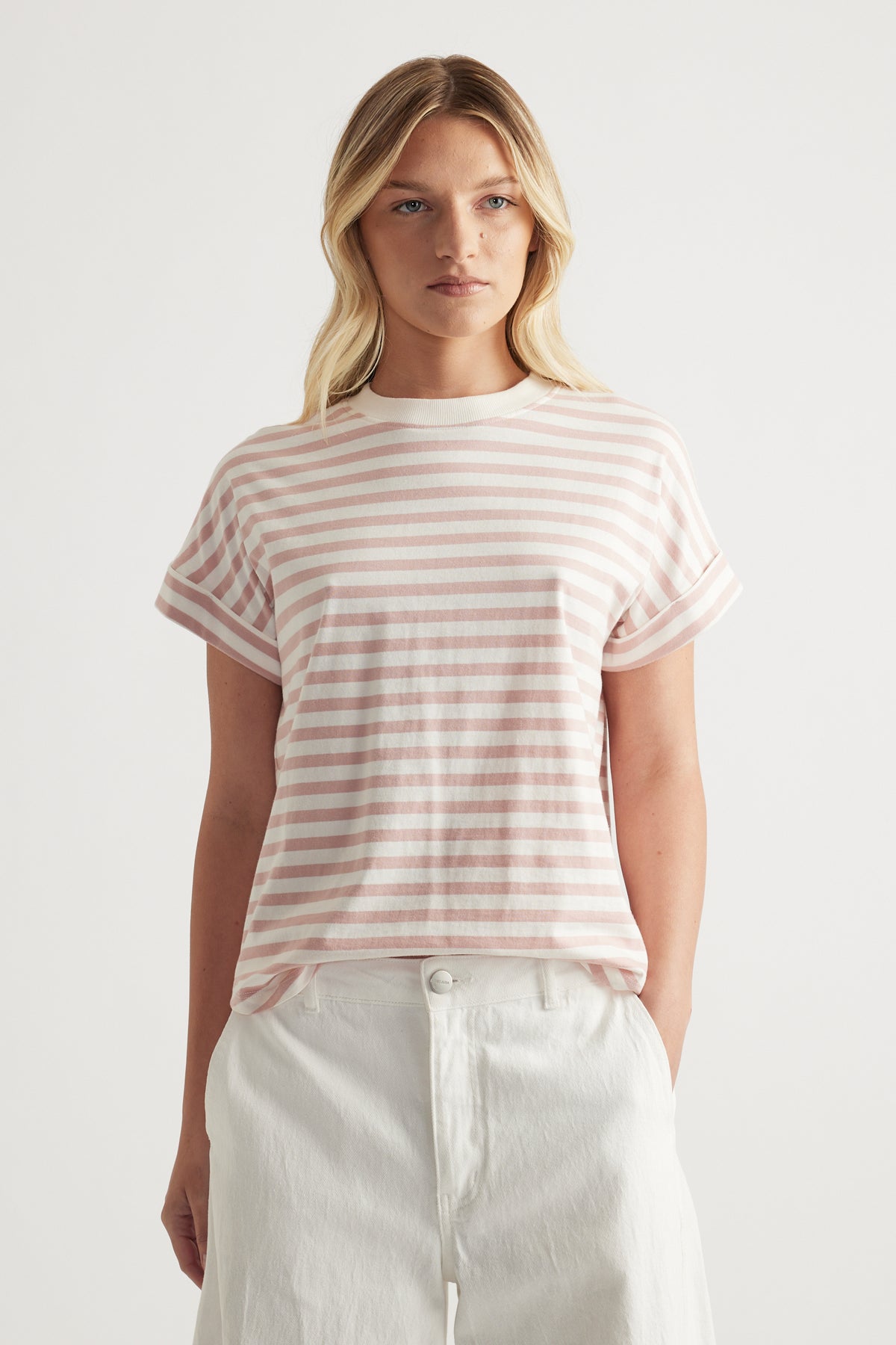 Woman wearing a pink and white striped crew neck tee with rolled cuffs and white pants