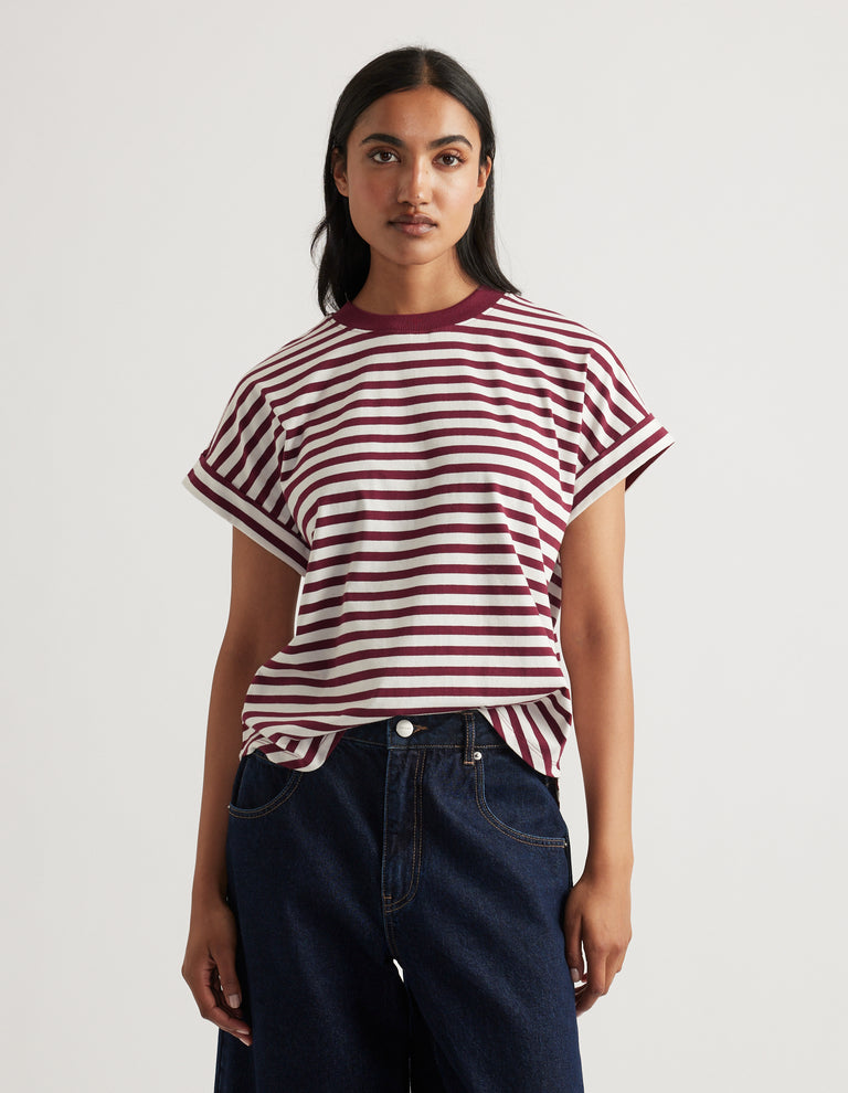 Woman wearing a relaxed fit crew tee with burgundy and white stripes paired with dark blue denim jeans