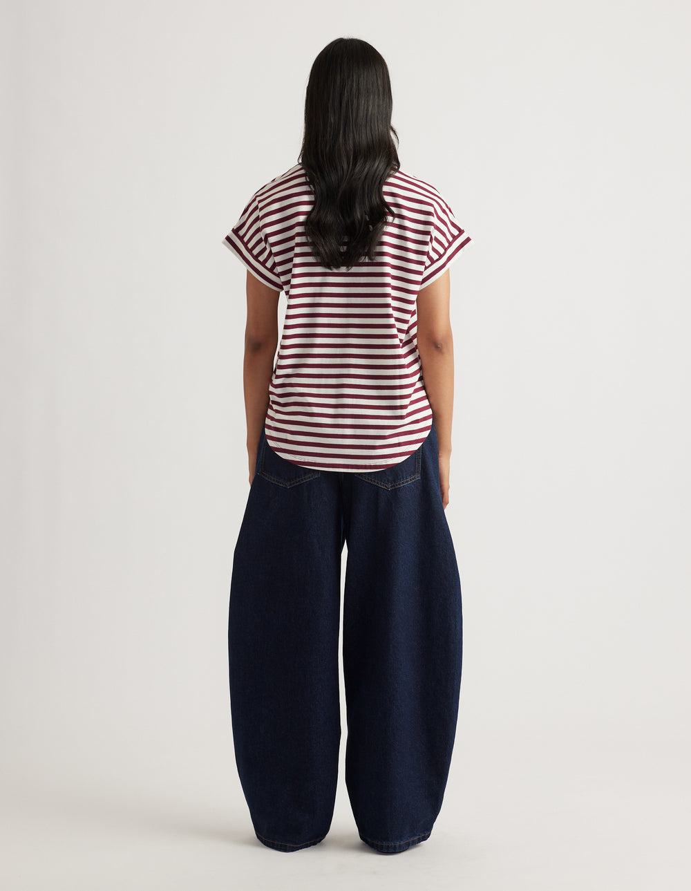 Woman wearing a relaxed fit striped tee with rolled sleeves paired with wide-leg dark denim jeans in a casual look