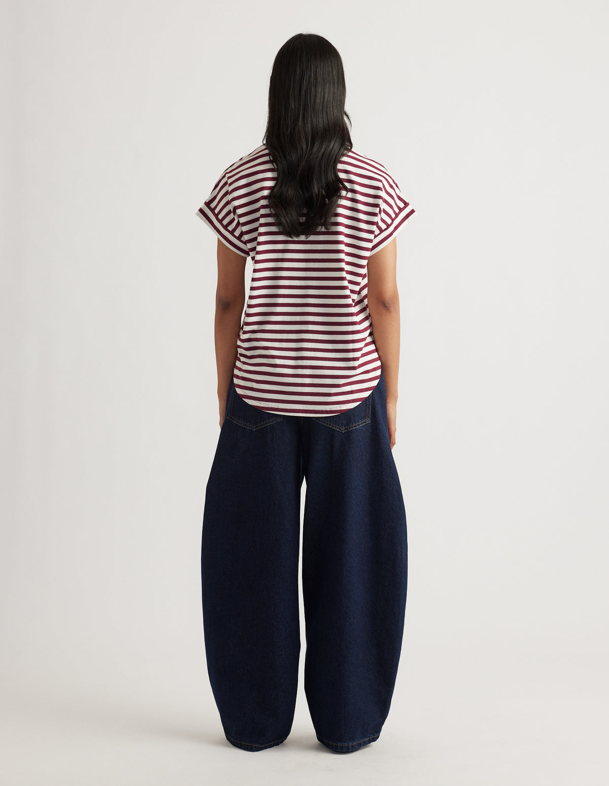 Woman wearing a relaxed fit striped tee with rolled sleeves paired with wide-leg dark denim jeans in a casual look