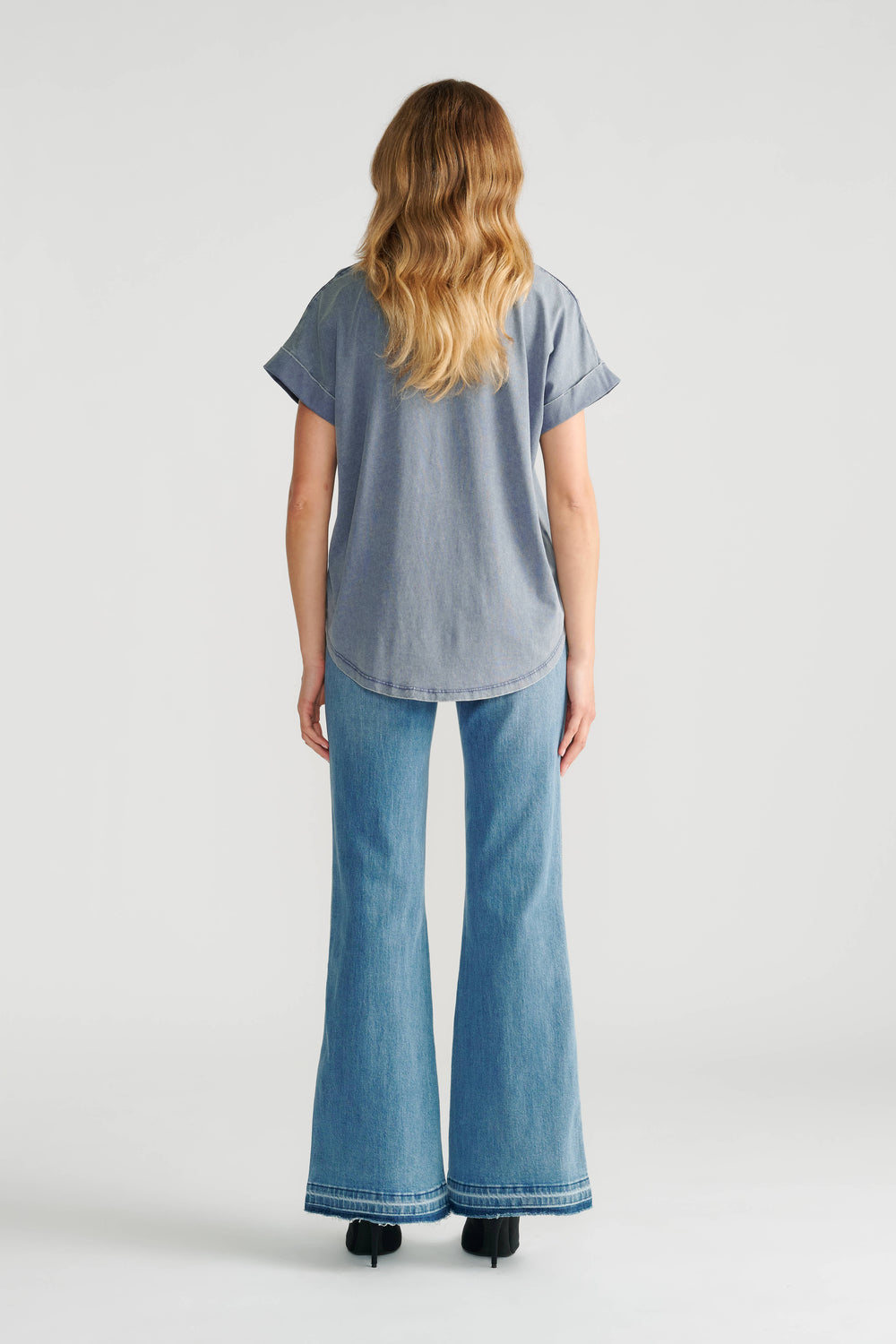 Woman wearing a relaxed-fit acid blue tee paired with high-rise light wash wide-leg denim jeans and black heels.