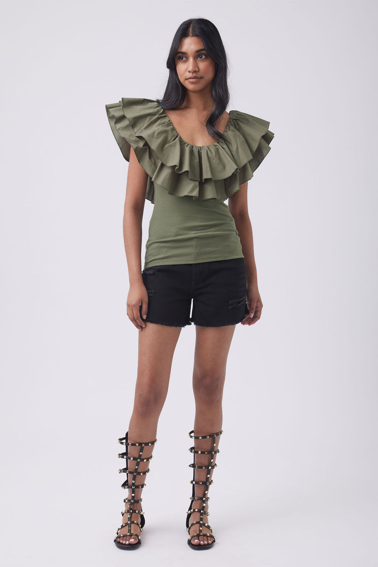 Woman wearing an olive green ruffle top, black shorts and strappy gladiator sandals