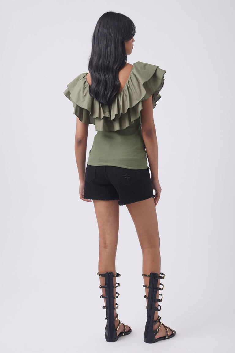 Woman wearing an olive green ruffle top with black shorts and strappy knee high boots