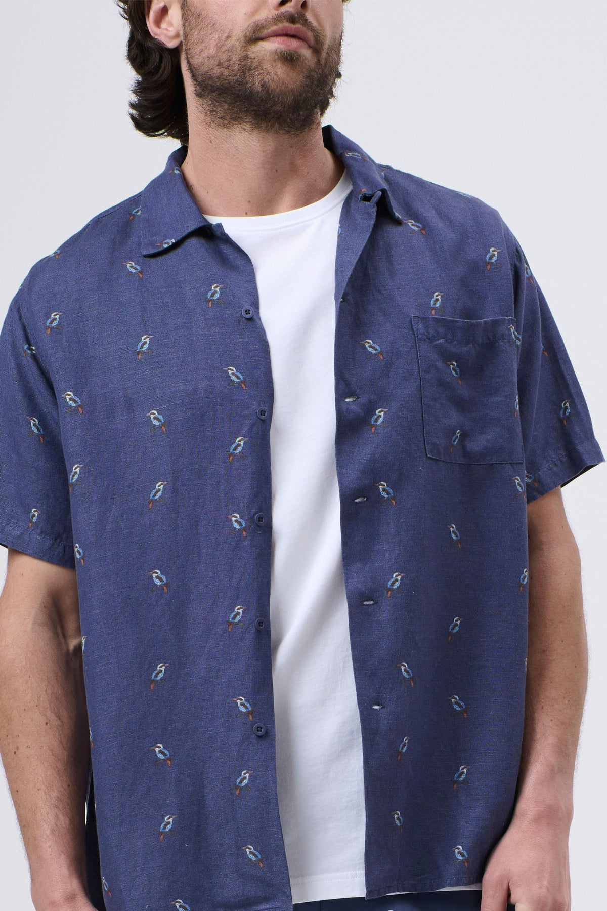 Man wearing a relaxed-fit navy blue short-sleeve shirt with small bird patterns over a white tee