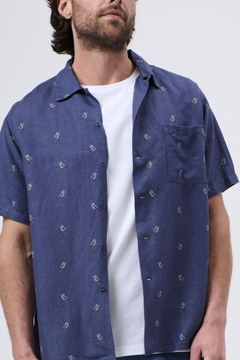 Man wearing a relaxed-fit navy blue short-sleeve shirt with small bird patterns over a white tee