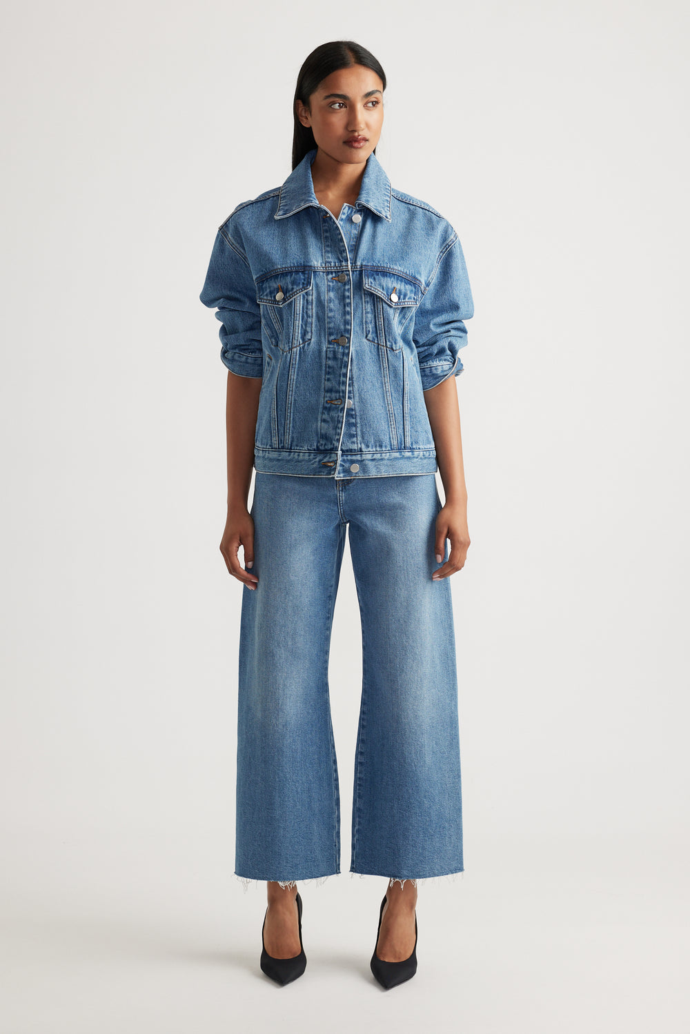 Model wearing Tahni Wide Leg Jean in medium blue denim with a relaxed fit paired with classic denim jacket by Decjuba Australian brand