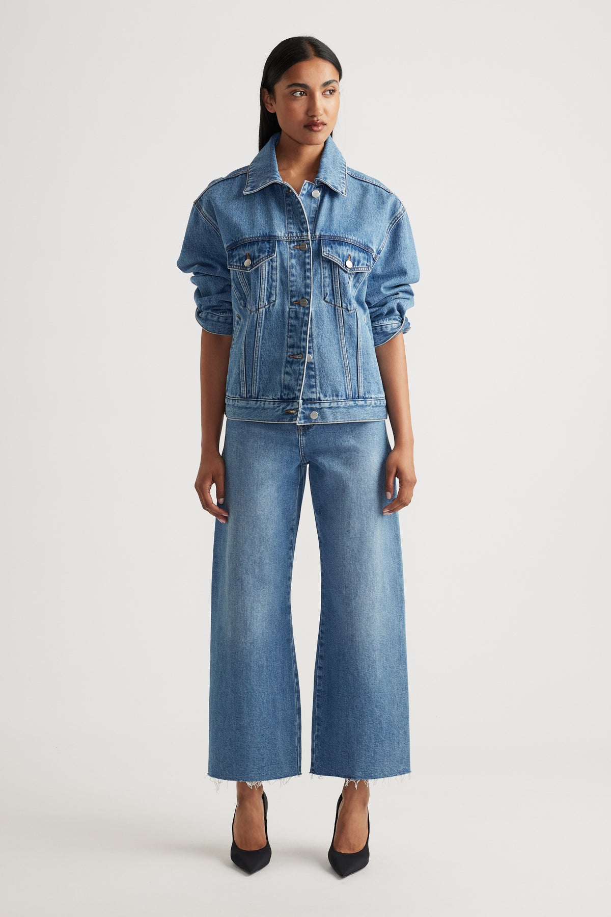 Model wearing Tahni Wide Leg Jean in medium blue denim with a relaxed fit paired with classic denim jacket by Decjuba Australian brand