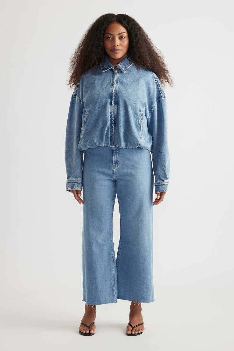 Woman wearing light blue high-rise wide-leg jeans with a cropped raw hem and strappy sandals