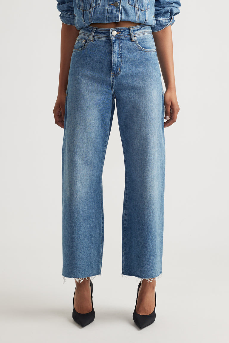 Woman wearing Tahni Wide Leg Jean with raw hem and a cropped denim jacket styled by Decjuba Australian brand