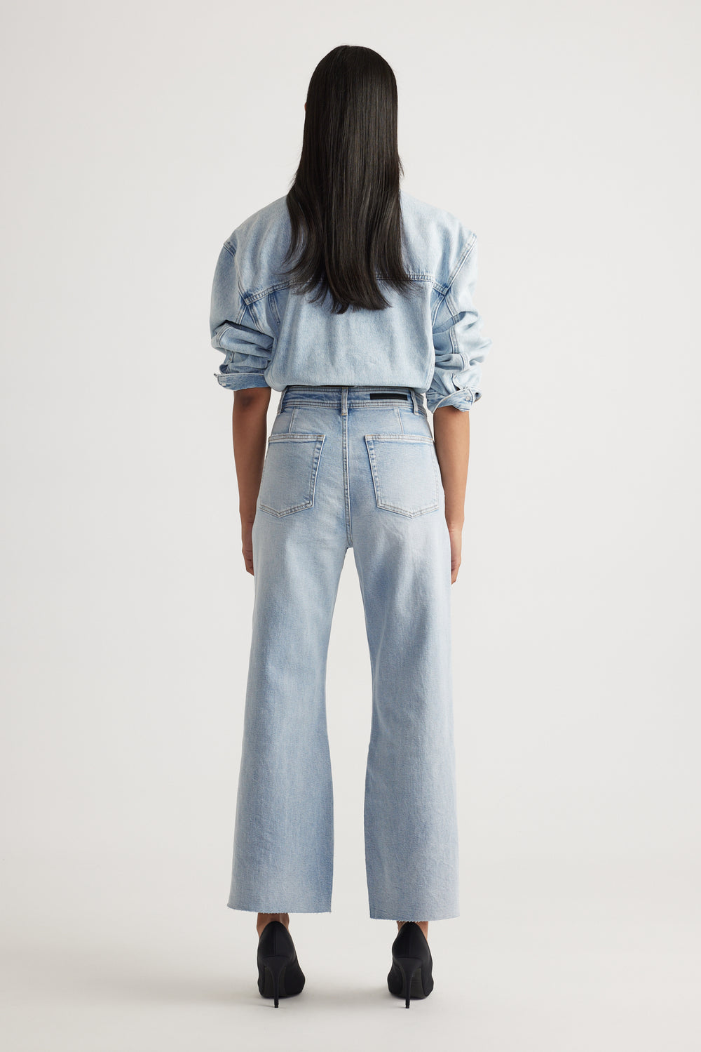 Rear view of woman wearing Tahni Wide Leg Jean in light denim styled with matching denim shirt by Decjuba Australian brand