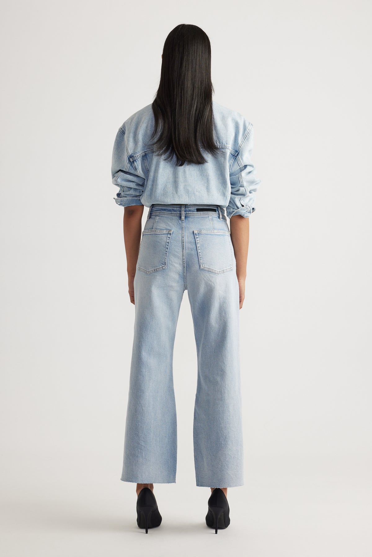Rear view of woman wearing Tahni Wide Leg Jean in light denim styled with matching denim shirt by Decjuba Australian brand