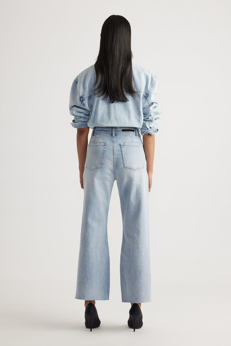 Rear view of woman wearing Tahni Wide Leg Jean in light denim styled with matching denim shirt by Decjuba Australian brand