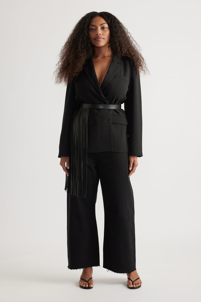 Woman wearing a black wrap top with waist belt, cropped wide leg jeans with raw hems, and strappy sandals