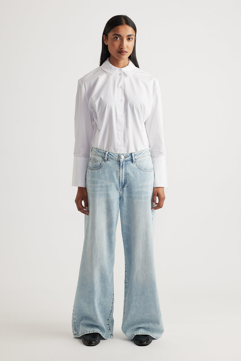 Front view of model wearing Jenna Palazzo Jean in light wash wide leg denim paired with crisp white shirt by Decjuba Australian brand