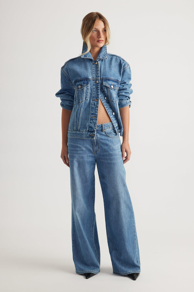 Model wearing Jenna Palazzo Jean in mid blue wide leg denim styled with casual denim jacket by Decjuba Australian brand