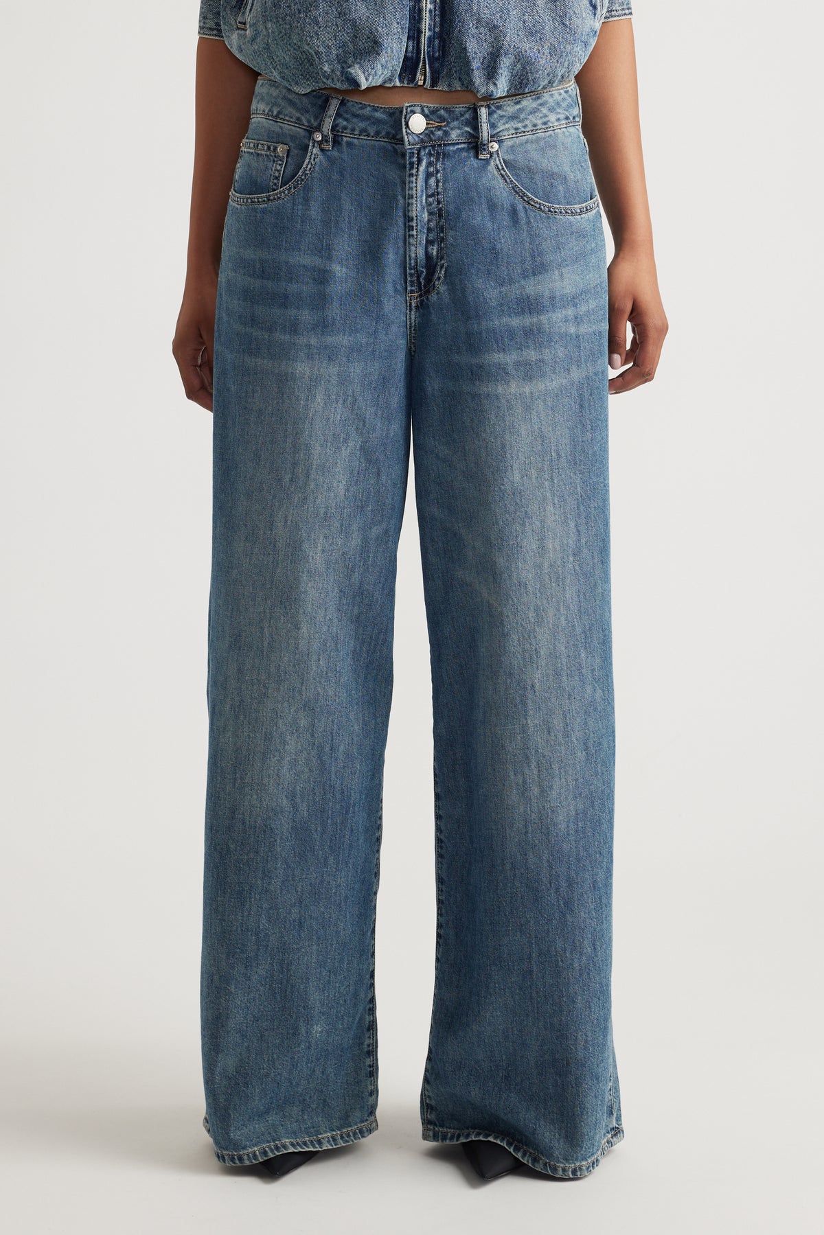Front view of mid rise wide-leg jeans in classic blue denim with subtle fading and traditional five-pocket styling