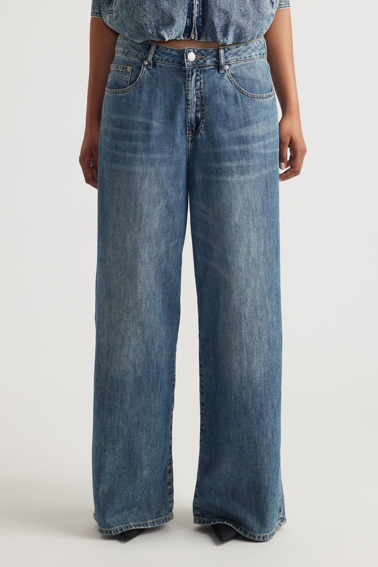 Front view of mid rise wide-leg jeans in classic blue denim with subtle fading and traditional five-pocket styling