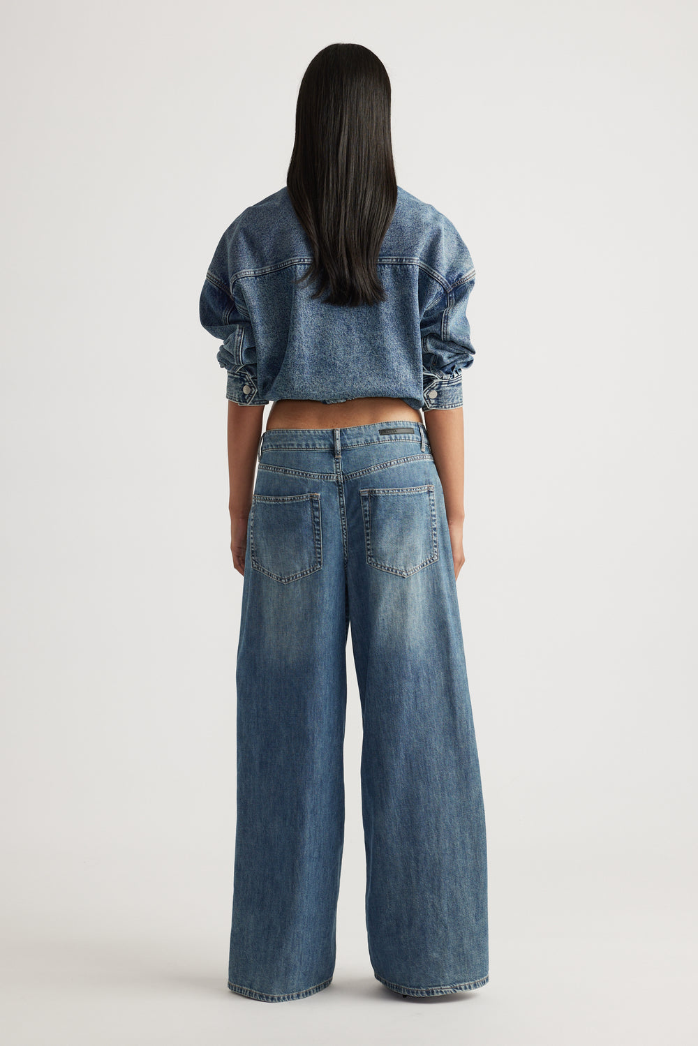 Rear view of model wearing Jenna Palazzo Jean in relaxed wide leg denim styled with cropped denim jacket by Decjuba Australian brand